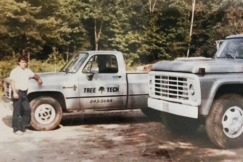 A man standing next to Tree Tech pick-up truck