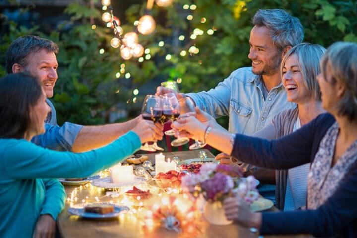 Group of adults at a dinner table clinking glasses of wine together