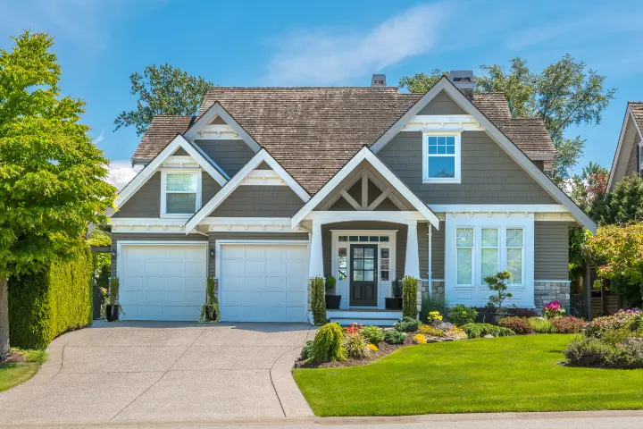 A large two-story home with a well-maintained lawn and surrounded by trees during Spring. How Preventative Plant Care Pays Off